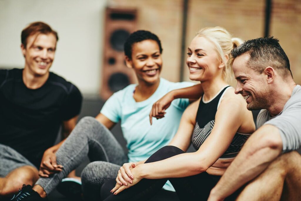 DIVERSE GYM GROUP SITTING TOGETHER AT THE GYM AFTER A WORKOUT CLASS